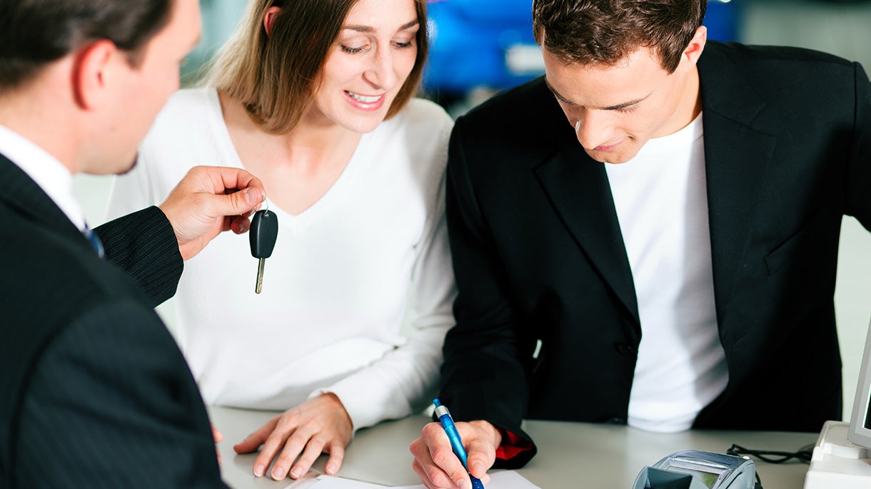 couple buying car with salesman